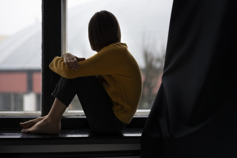 Person sitting alone reflecting on independence and loneliness, symbolizing emotional struggle and need for support.