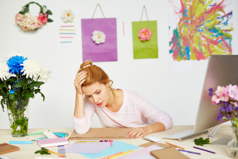 Person sitting at a desk feeling overwhelmed by unfinished tasks, illustrating the connection between ADHD and procrastination.