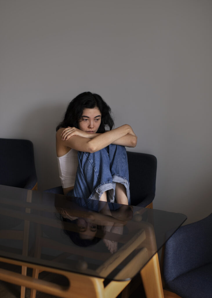 A grieving woman sitting alone in a quiet room, reflecting on loss while receiving emotional support and counselling guidance from an NGO in India.