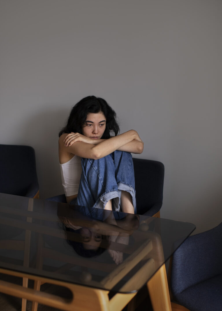 A grieving woman sitting alone in a quiet room, reflecting on loss while receiving emotional support and counselling guidance from an NGO in India.