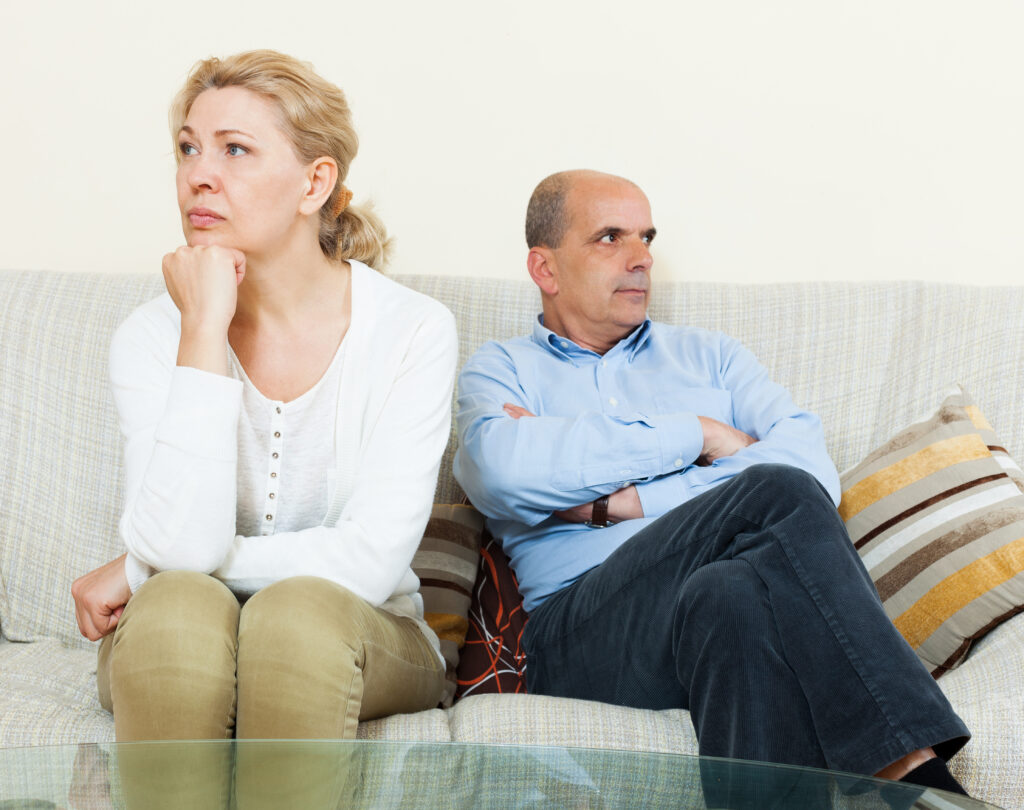 An elderly couple sitting apart on a park bench, reflecting on the emotional challenges of considering divorce in old age.