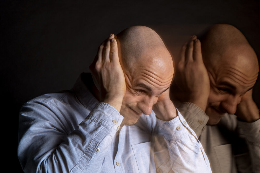 Elderly person experiencing symptoms of late-onset schizophrenia, appearing confused and distressed while sitting alone at home.