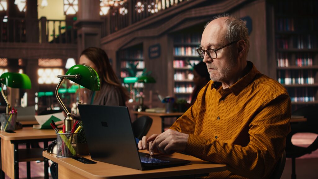 Older adult learning digital literacy on a laptop with guidance, building confidence in using technology safely every day.