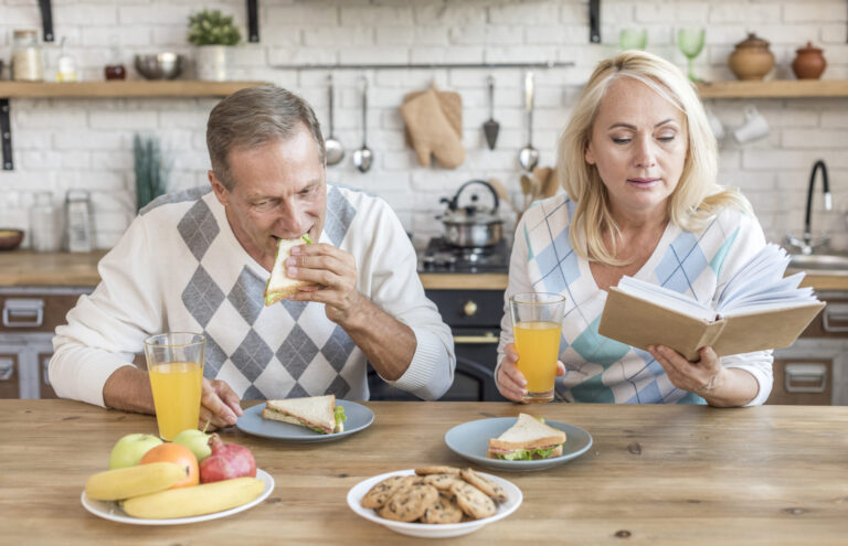 Medium shot of a couple in a kitchen with a book, featuring contrasting colors and deep lighting.